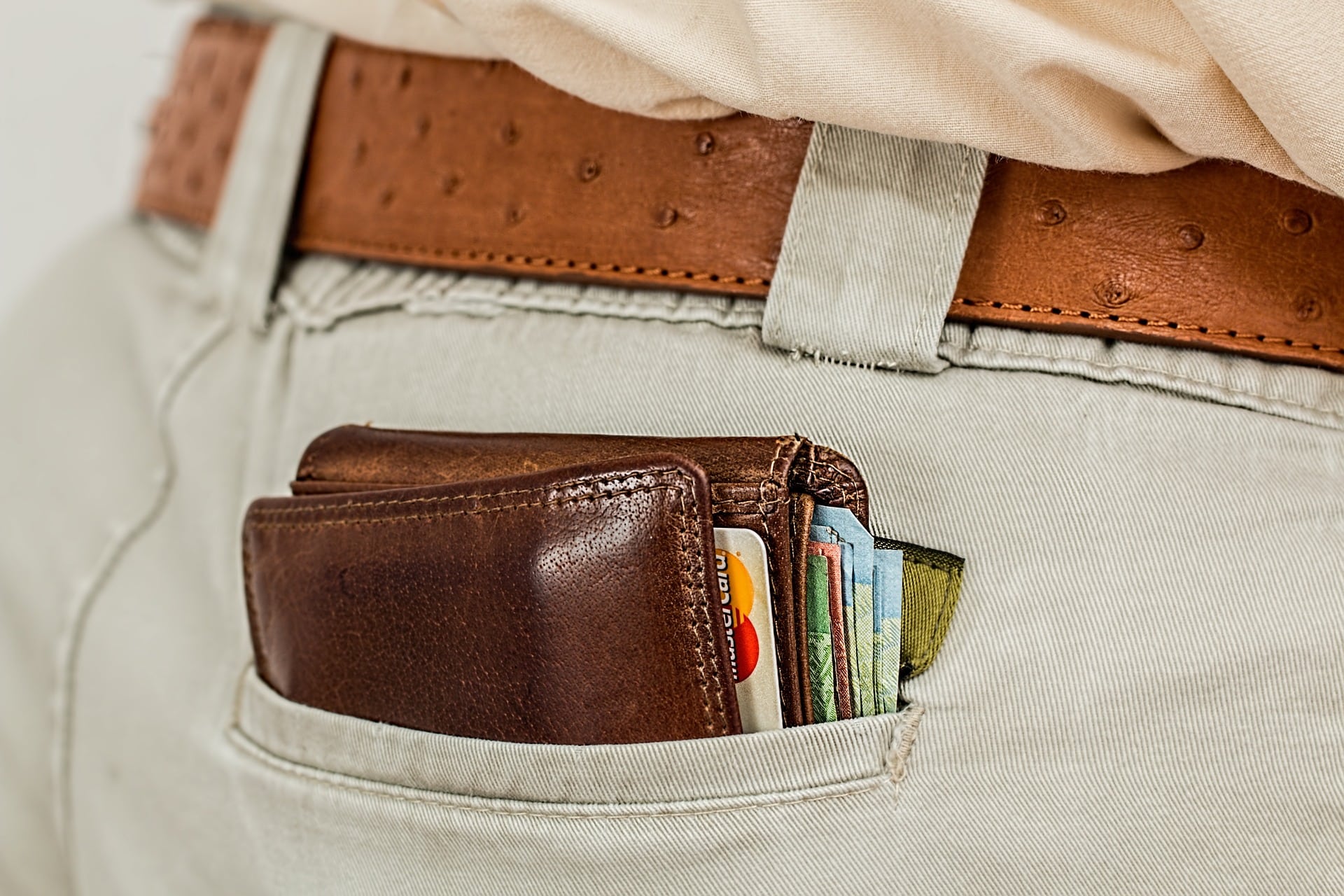 reduzir a inadimplência: carteira no bolso com dinheiro e cartões simbolizando a redução